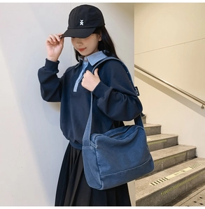 Détail du grand sac cabas en jean bleu avec bandoulière réglable porté par un mannequin