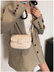 Close-up of cream square crossbody bag with lychee texture and gold metal hardware