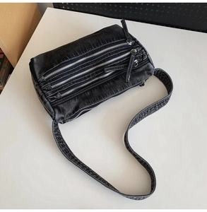 Detail of washed black denim tote bag with triple metal zippers and punk-style texture