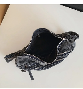 Detail view of washed denim tote bag showing internal pockets and multi-zipper structure