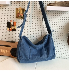Détail du sac hobo en jean bleu avec bandoulière réglable et poche avant sur panneau
