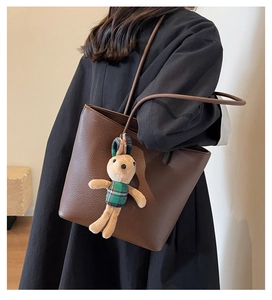 Detail of dark brown lychee leather tote bag with long straps and plush rabbit charm