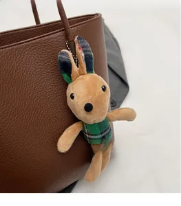Brown plush bunny charm with plaid details hanging on a brown pebbled leather tote bag