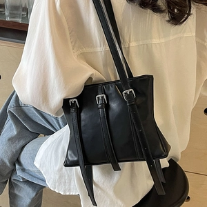 Grand sac cabas noir en cuir avec sangles verticales décoratives porté à l'épaule par un mannequin