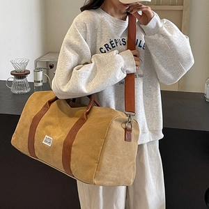 Large khaki canvas travel bag with brown leather handles and adjustable shoulder strap