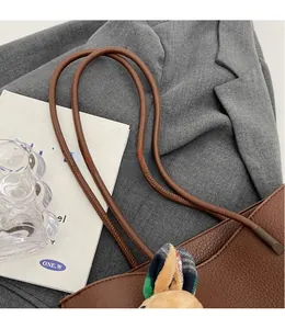Detail of smooth caramel leather tote shoulder strap with cute bunny charm accessory