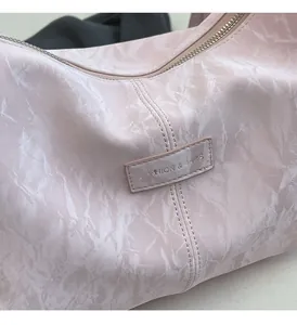 Detail der Tragetasche mit rosa Marmormuster und dem Fashion & Bags-Metallemblem