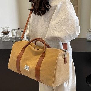 Large khaki canvas duffel bag with brown leather handles and adjustable shoulder strap