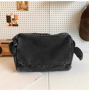 Gros plan d'un sac cabas en jean noir montrant la texture délavée et les détails de sangle