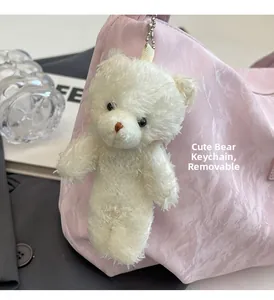 Detail eines abnehmbaren weißen Plüschbär-Anhängers an einer rosa Tasche mit Silberkette