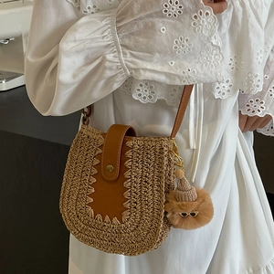 French woven straw bucket bag with brown leather flap and cute plush charm for beach vacation