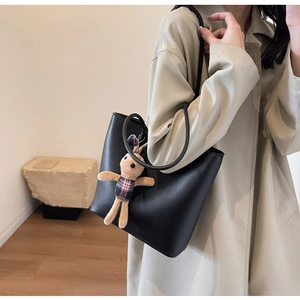 Close-up of black litchi pattern leather tote bag with cute rabbit charm detail