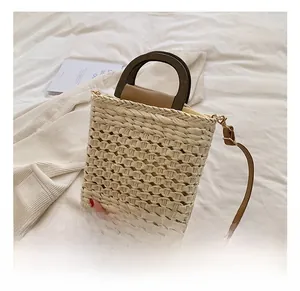 Detail of woven straw bag showing wooden handle, leather strap, and intricate mesh texture
