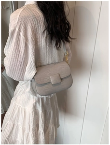 Litchi pattern leather crossbody bag detail on model wearing white layered dress