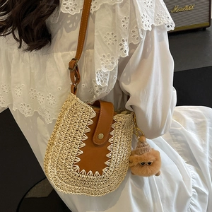 French straw woven bucket bag with brown leather trim shown on shoulder of a model
