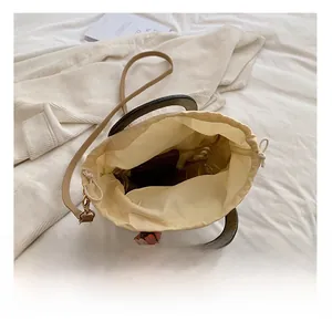 Detail view of woven straw bucket bag showing large interior capacity and wooden handles