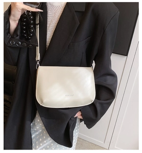 Vue détaillée du petit sac bandoulière en cuir crème porté sur un blazer noir élégant