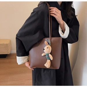 Detail of dark brown pebble leather tote bag featuring a plush rabbit charm accessory