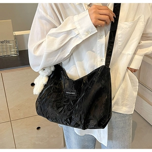 Detailansicht der großen schwarzen Hobo-Tasche mit Falten, Bären-Anhänger und Etikett