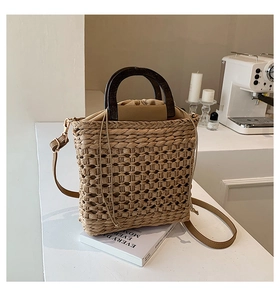 Detail of woven straw bag with round wooden handles and adjustable leather shoulder strap