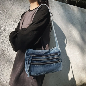 Blue denim tote bag with triple zipper layers and cross-body strap for casual commuting