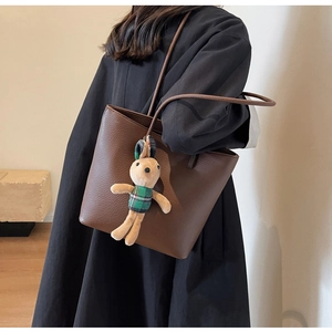 Close-up of brown litchi pattern leather tote bag with a cute rabbit plush pendant