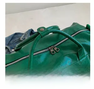 Detail of green embossed leather travel bag featuring comfortable handles and double zippers