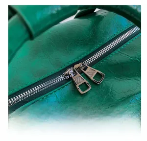 Macro shot of smooth metal double zippers on emerald green leather travel bag