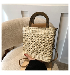 Detailed view of hand-woven straw bag with round wooden handles and faux leather strap