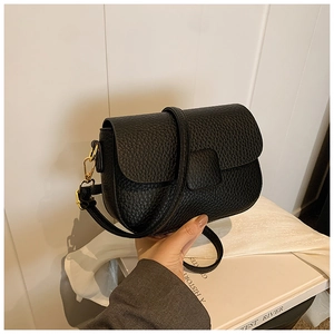 Close-up of black lychee texture leather shoulder bag with elegant gold hardware details