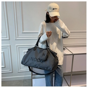 Large dark grey gym bag with NOCO logo and a matching mini pouch shown on a model