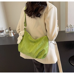 Detail der grünen Plissee-Samt-Tote-Bag mit einem niedlichen weißen Plüschbär-Anhänger