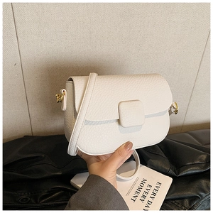 Detailed macro view of white pebble grain leather handbag with gold metal hardware