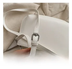 Détail de la bandoulière réglable avec boucle en métal argenté sur un sac blanc