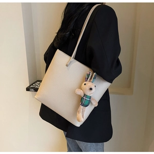 Close-up of cream tote bag with lychee texture leather and a plaid rabbit charm