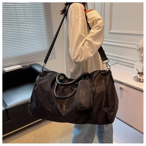 Detail of high-capacity black gym bag showing leather handles and detachable shoulder strap