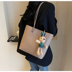 Taupe pebbled leather tote bag with a cute rabbit charm shown on model's shoulder