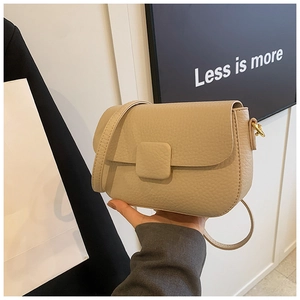 Detail of beige lychee leather saddle bag with gold-tone hardware and square buckle