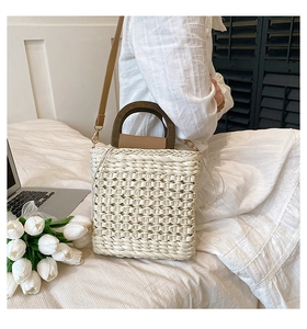 Detail view of woven straw beach bag with wooden handle and drawstring inner liner