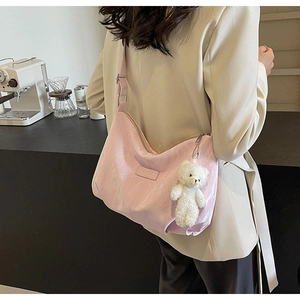 Rosa Samt-Hobo-Tasche mit Bärenanhänger, präsentiert von einem Model im Café-Ambiente