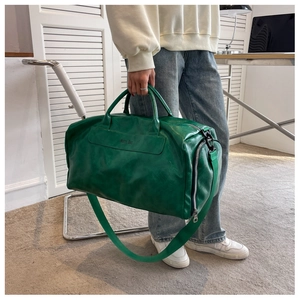 Close-up of green PU leather travel bag showing texture and adjustable shoulder strap
