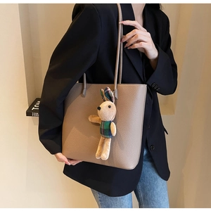 Close-up of litchi grain leather tote bag featuring a cute plush bunny charm detail