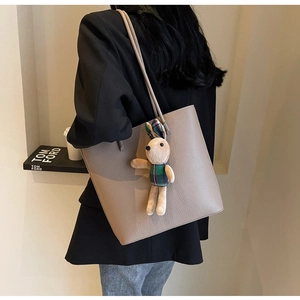 Detail of grey pebble leather tote bag with a cute plush rabbit charm on the strap