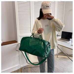 Green leather duffel bag with dual handles and adjustable strap for gym or travel