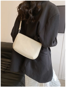 Sac à bandoulière blanc cassé moderne porté avec un blazer noir au style minimaliste