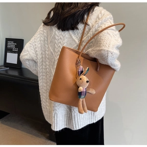 Detailed texture of brown pebble leather tote bag featuring a cute plaid bunny charm