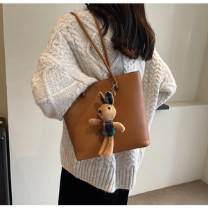Close-up of brown litchi pattern leather tote bag with a cute plush rabbit charm