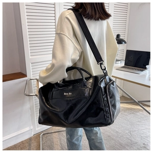 Detail of glossy black travel bag with adjustable strap and brand logo in a home setting