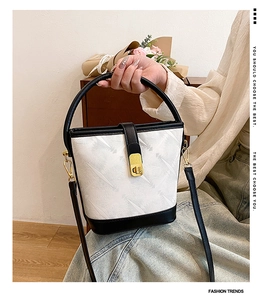 Close-up of black and white leather bucket bag with gold rotating metal lock and handle