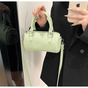 Detail of pistachio green cylindrical mini bag with vertical embossed texture and silver hardware